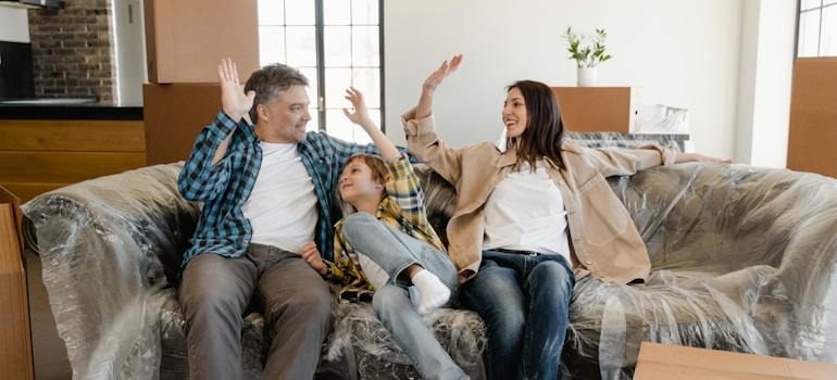 A family of three, sitting on a couch after relocating with reputable Sterling movers
