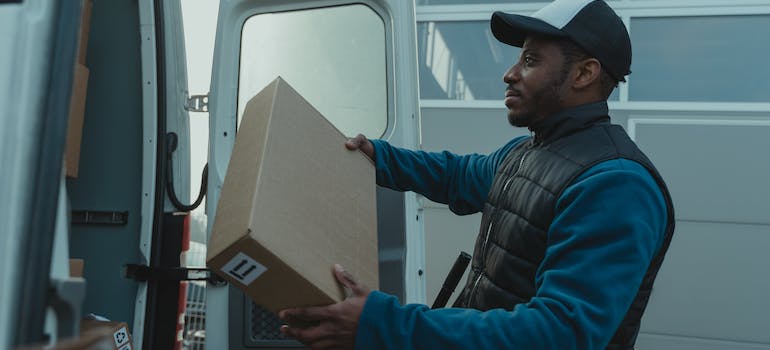 One of interstate movers in landover md loading a box into a moving truck.