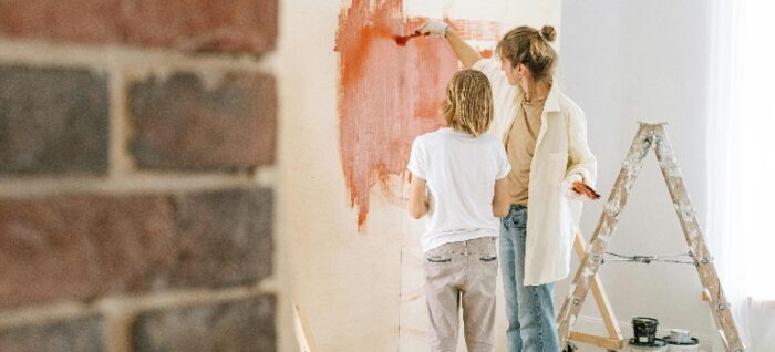 two women painting a wall 