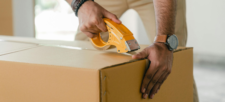 person taping a cardboard box