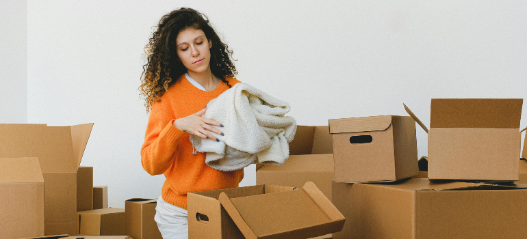 woman taking clothes out of a cardboard box after reading the tips for a secure and organized move