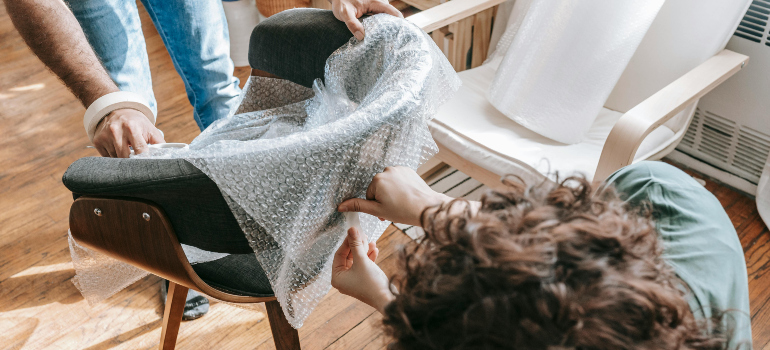 people covering a chair with bubble wrap understanding common moving mistakes and how to avoid them