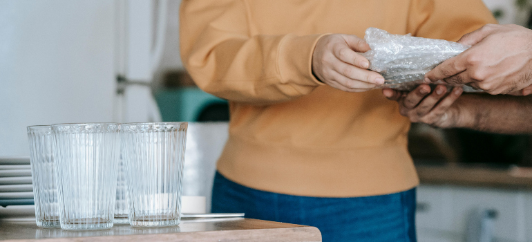 two people wrapping plates in bubble wrap