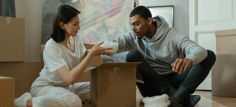 couple unpacking boxes with room-by-room unpacking strategies