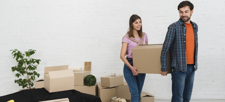 A man and woman are lifting boxes and talking about hiring movers in Chevy Chase.