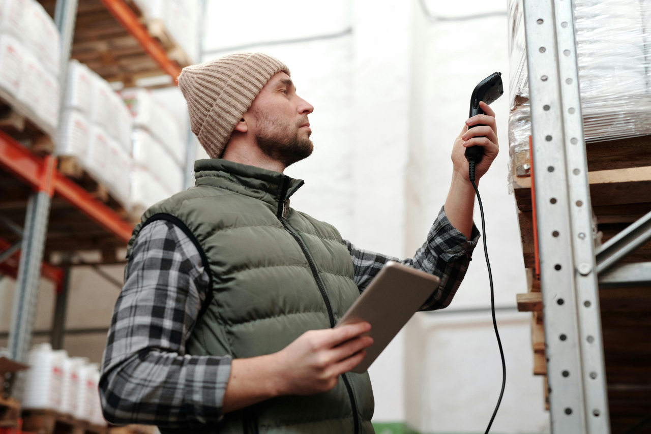 Warehouse worker scanning items in a storage facility while holding a tablet.