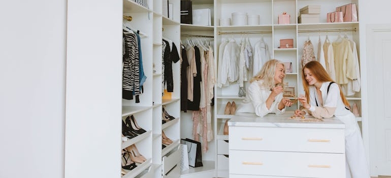 two women in a closet deciding what to leave behind when moving