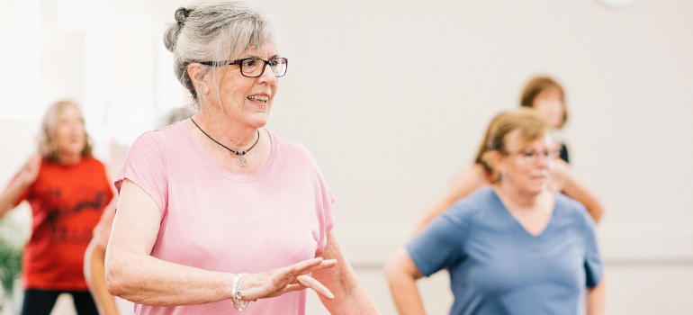 A group of senior women participating in a fitness class, enjoying the benefits of senior housing 