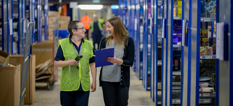 A manager and worker walking through a warehouse, emphasizing trust in the freight forwarding industry for dependable service.
