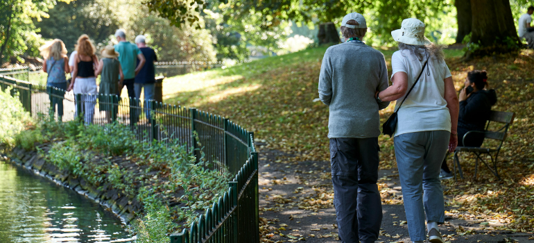 Seniors walking together along a scenic park path, talking about the benefits of senior housing 
