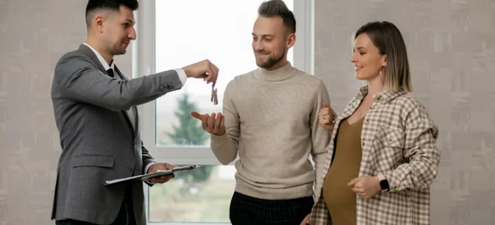 a real-estate agent giving the keys of a house to a couple 