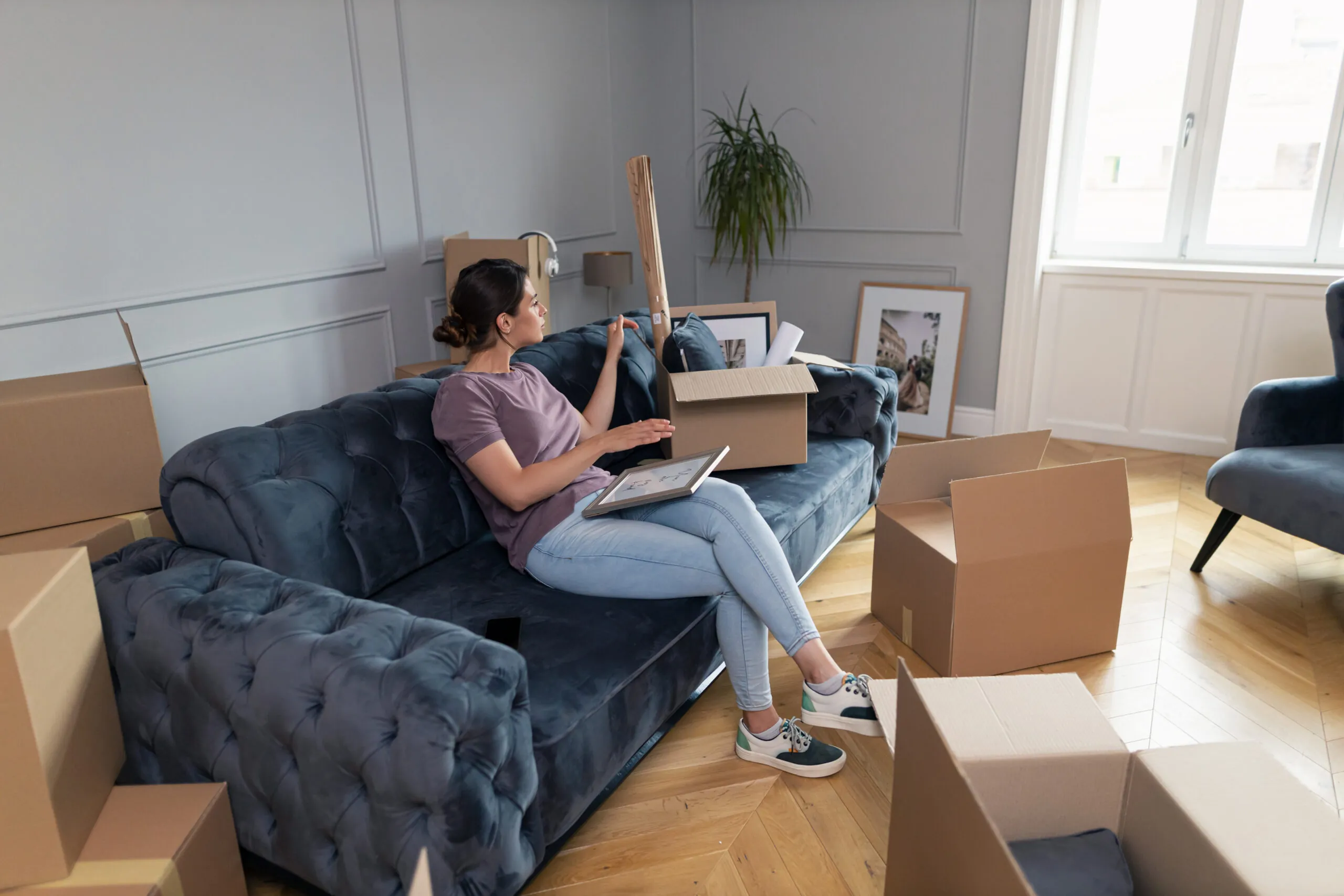 Lading sitting on couch moving furniture